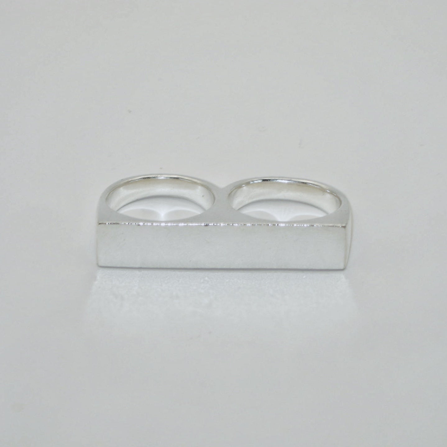 Silver knuckle duster signet ring on a light grey background