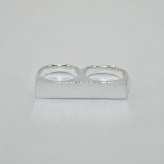 Silver knuckle duster signet ring on a light grey background