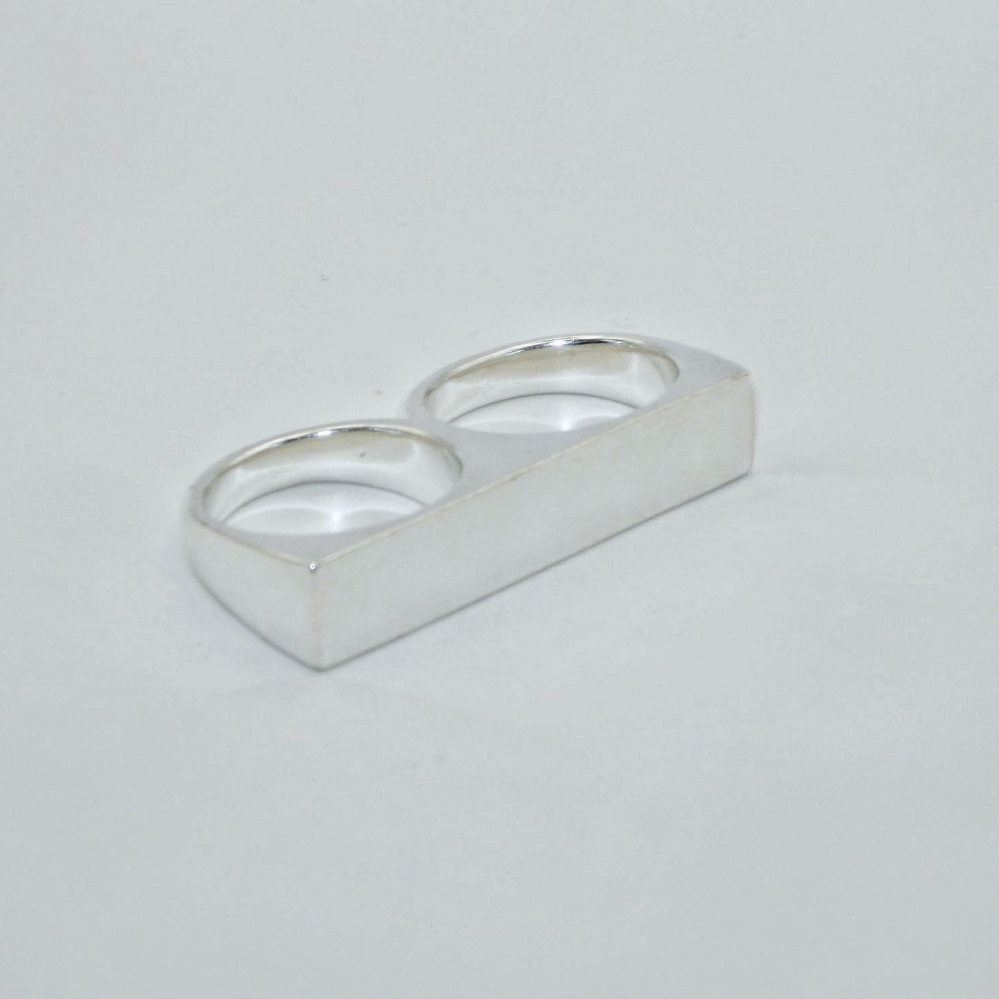 Silver knuckle duster signet ring on a light grey background