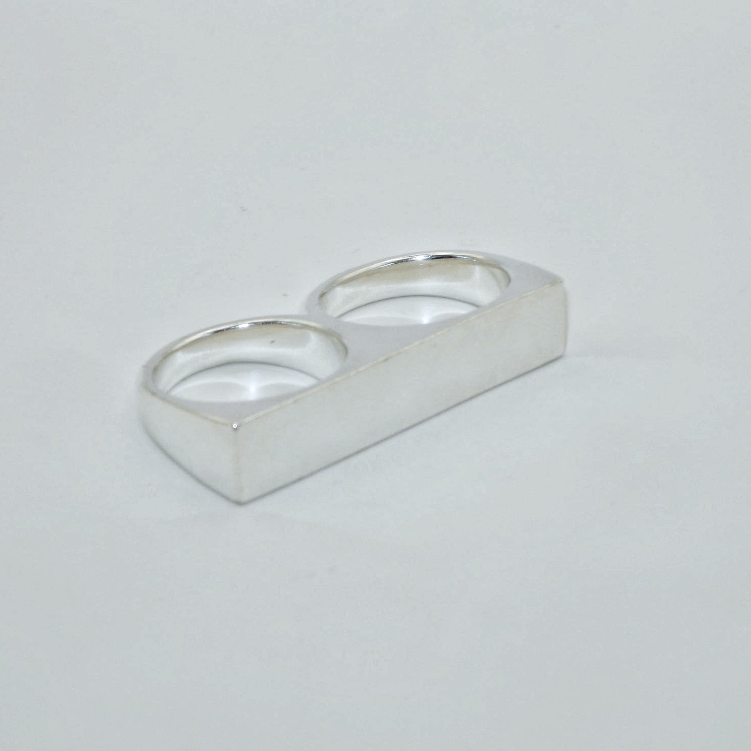 Silver knuckle duster signet ring on a light grey background